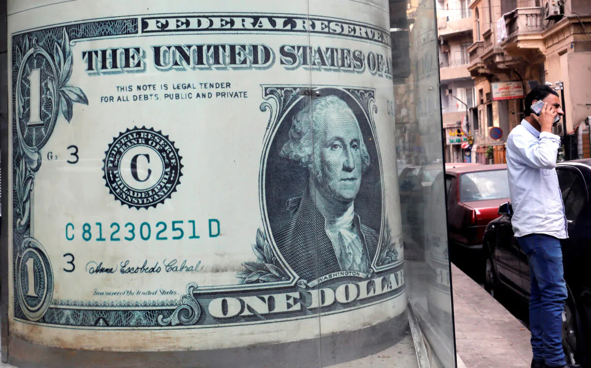 A man talks on his mobile phone in front of a currency exchange bureau advertisement showing images of the U.S. dollar in Cairo, Egypt, on Dec. 17, 2019. (Reuters/Amr Abdallah Dalsh)
