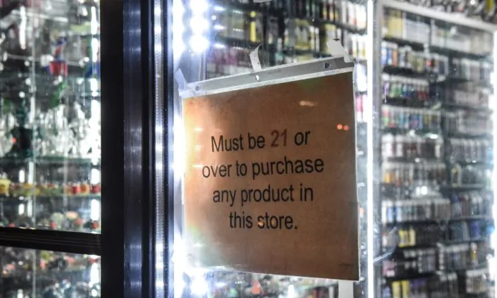 A sign that states "must be over 21" hangs in the store window of a vape shop in New York City on Dec. 19, 2019. (Stephanie Keith/Getty Images)