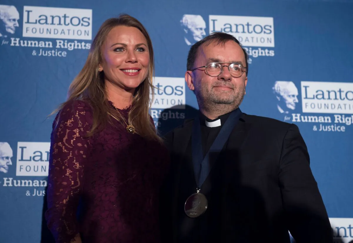 Lara Logan, chief foreign affairs correspondent for CBS News, presents Father Patrick Desbois with the Lantos Human Rights Prize during a ceremony on Capitol Hill in Washington on Oct. 26, 2017, to honor his work and foundation, Yahad-In Unum, in researching and uncovering genocidal practices around the world. (SAUL LOEB/AFP via Getty Images)