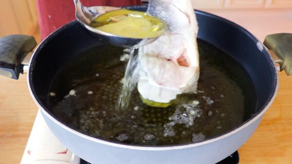 Ladling the oil over fish