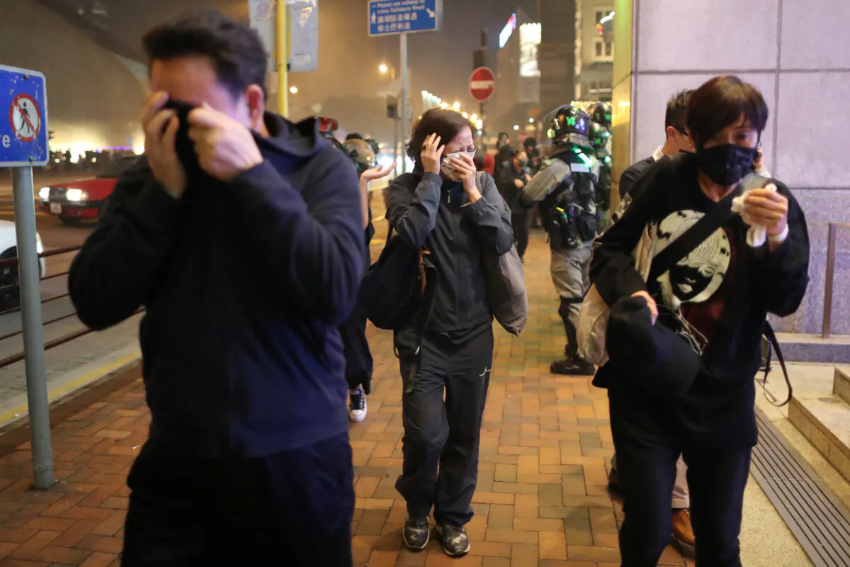 People run away from tear gas during a Christmas Eve Hong Kong protest march outside the Harbour City mall in Hong Kong, on Dec. 24, 2019. (Lucy Nicholson/Reuters)