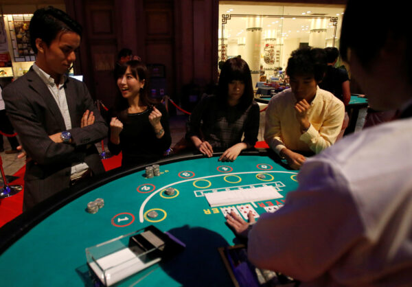 Visitors react after they win a mock baccarat casino game at an international tourism promotion symposium in Tokyo