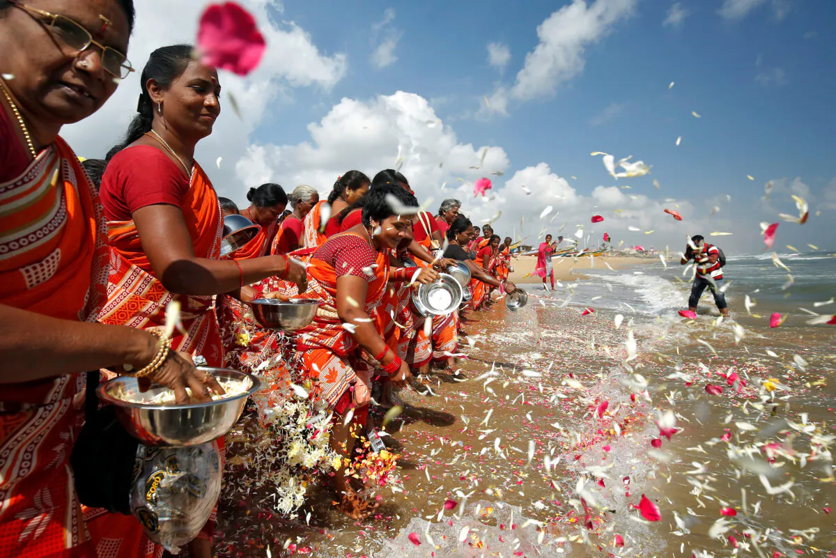 Women scatter flower petals in the waters of the Bay of Bengal during a prayer ceremony for the victims of the 2004 tsunami on the 15th anniversary of the disaster, at Marina beach in Chennai, India, on Dec. 26, 2019. (P. Ravikumar/Reuters)
