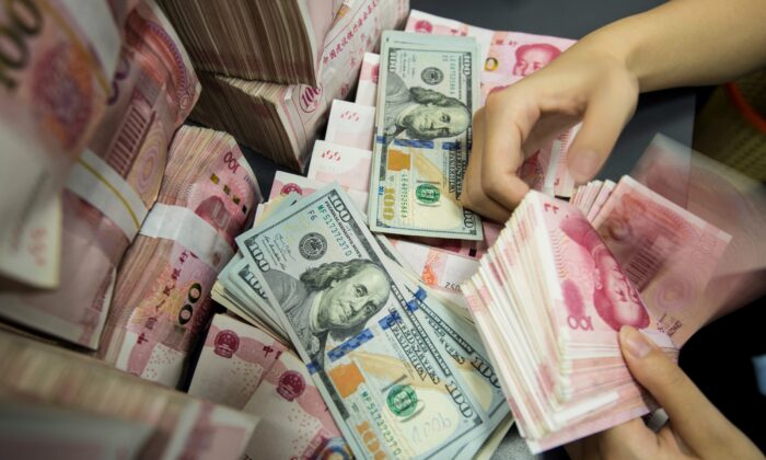 A Chinese bank employee counts 100-yuan notes and US dollar bills at a bank counter in Nantong in China's eastern Jiangsu Province on Aug. 28, 2019. (STR/AFP/Getty Images)