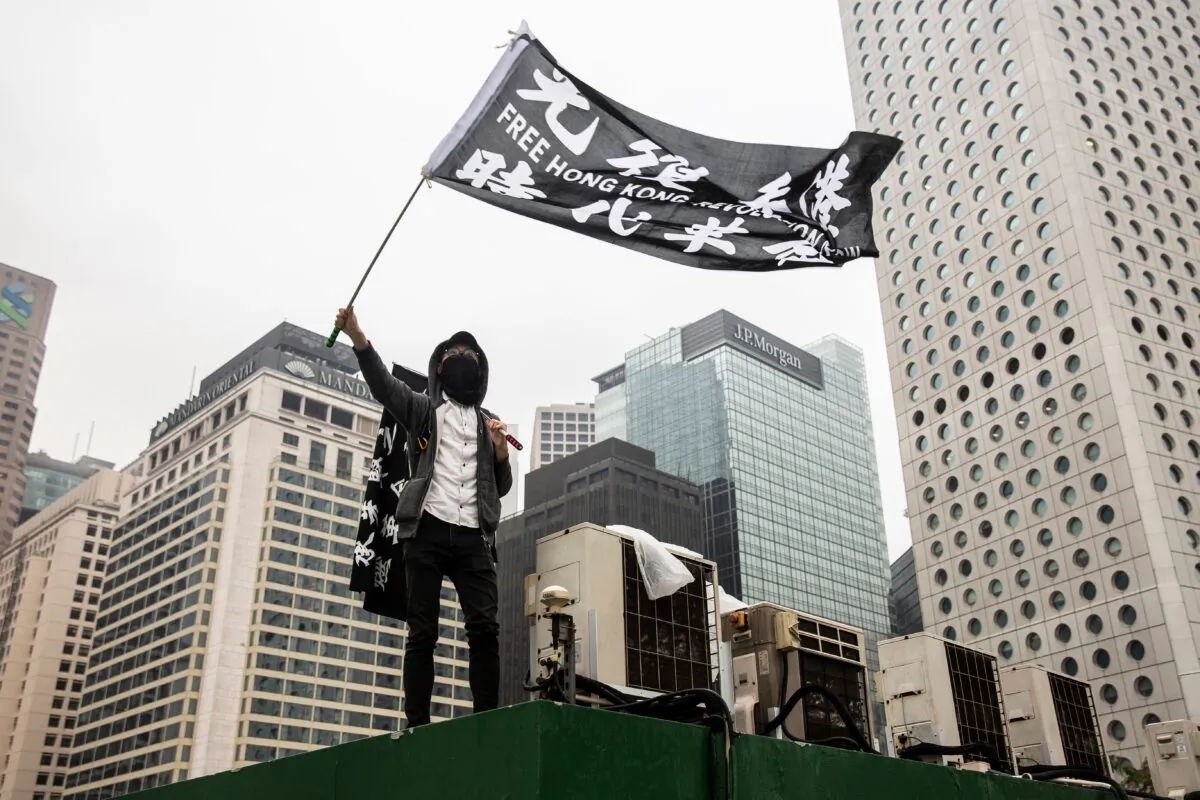 Protesters wave flags on top of a car park during a gathering at Edinburgh Place in the Central district of Hong Kong on Dec. 29, 2019. One of the targeted NGOs is reportedly a human rights group that has  (Isaac Lawrence/AFP via Getty Images)