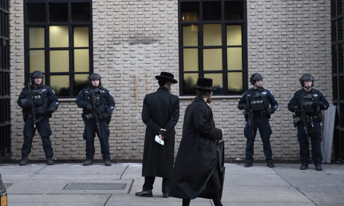 Orthodox Jewish men pass New York City police guarding a Brooklyn synagogue prior to a funeral for Mosche Deutsch in New York on Dec. 11, 2019. (Mark Lennihan/AP Photo)