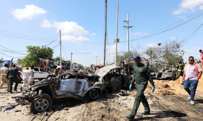 A Somali police officer walks past a wreckage at the scene of a car bomb explosion at a checkpoint in Mogadishu, Somalia, on Dec. 28, 2019. (Reuters/Feisal Omar)
