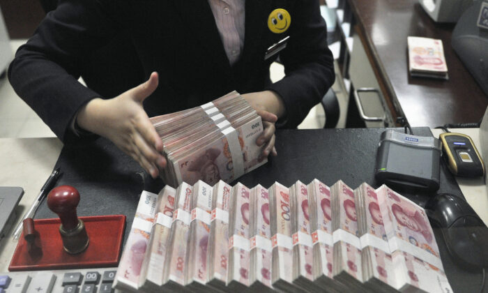 A clerk arranges bundles of 100 Chinese yuan banknotes at a branch of China Merchants Bank in Hefei, Anhui Province, China on March 17, 2014. (Reuters)