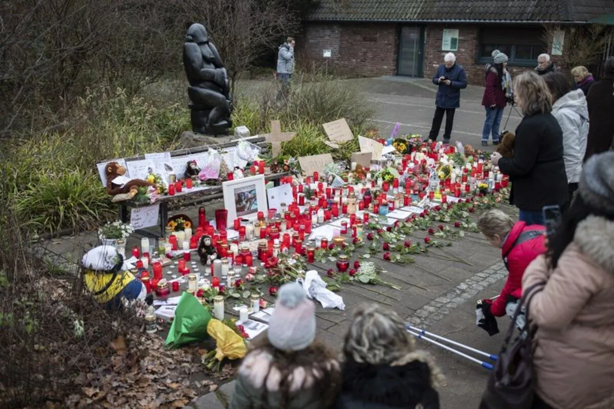 A woman lights a candle at the main entrance of the zoo in Krefeld, Germany on Jan. 2, 2020. (Marcel Kusch/dpa via AP)