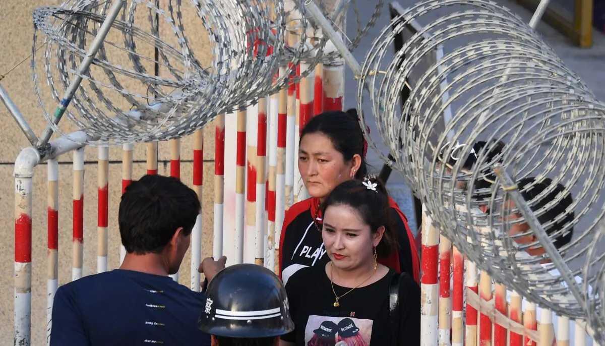 This photo taken on May 31, 2019 shows a Uighur woman (C) going through an entrance to a bazaar in Hotan, in China's northwest Xinjiang region. - A recurrence of the Urumqi riots which left nearly 200 people dead a decade ago is hard to imagine in today's Xinjiang, a Chinese region whose Uighur minority is straitjacketed by surveillance and mass detentions. A pervasive security apparatus has subdued the ethnic unrest that has long plagued the region. (Photo by GREG BAKER / AFP) (Photo credit should read GREG BAKER/AFP via Getty Images)