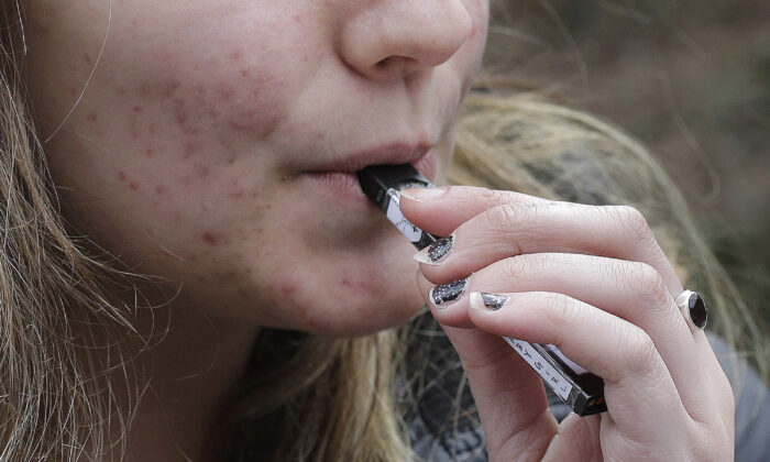 A high school student uses a vaping device near a school campus in Cambridge, Massachusetts, on April 11, 2018. (Steven Senne/AP Photo)
