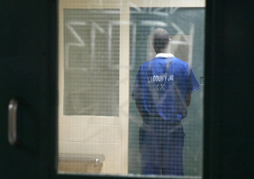 A prisoner waits in a holding cell in the Twin Towers Correction Facility during a media tour of the facility and the adjacent Los Angeles Men's Central Jail in downtown Los Angeles on May 19, 2004. (Robyn Beck/AFP via Getty Images)