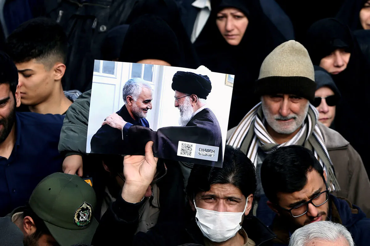 A demonstrator holds a picture of Supreme Leader Ayatollah Ali Khamenei with Iranian Major-General Qassem Soleimani, during protest against the killing of Soleimani, head of the elite Quds Force, and Iraqi militia commander Abu Mahdi al-Muhandis who were killed in an air strike in Baghdad airport, in Tehran, Iran on Jan. 3, 2020. (WANA/Nazanin Tabatabaee via Reuters)