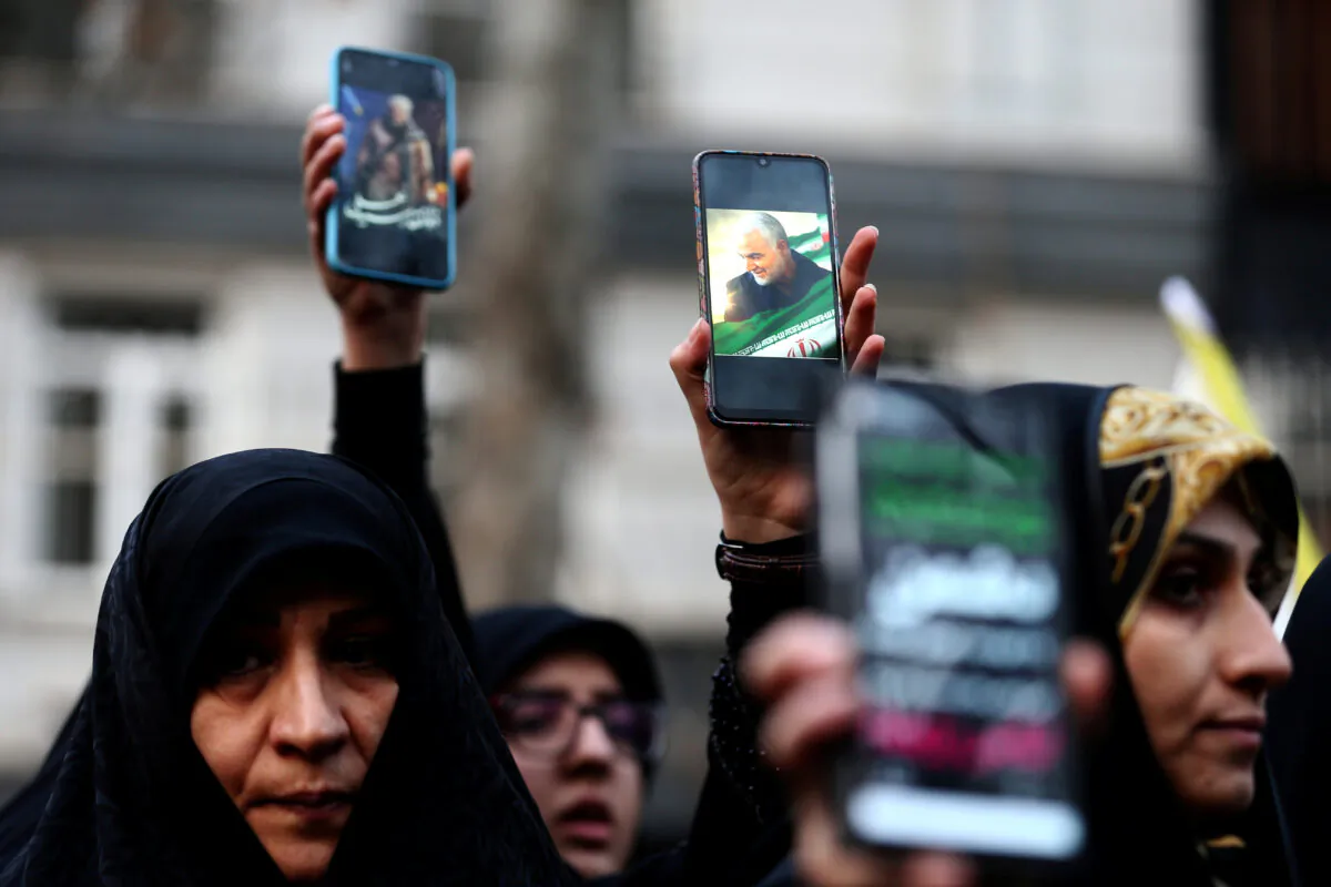 Iranian demonstrators hold up mobile phones showing the picture of the late Iranian General Qassem Soleimani, during a protest against the killing of Soleimani, head of the elite Quds Force, and Iraqi militia commander Abu Mahdi al-Muhandis, who were killed in an air strike at Baghdad airport, in front of United Nations office in Tehran, Iran, on Jan. 3, 2020. (Nazanin Tabatabaee/WANA (West Asia News Agency) via Reuters)