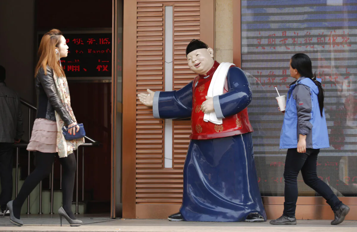 People walk past a statue, placed there to promote a restaurant, at a shopping district in Beijing, China on April 3, 2013. (Kim Kyung-Hoon/Reuters)