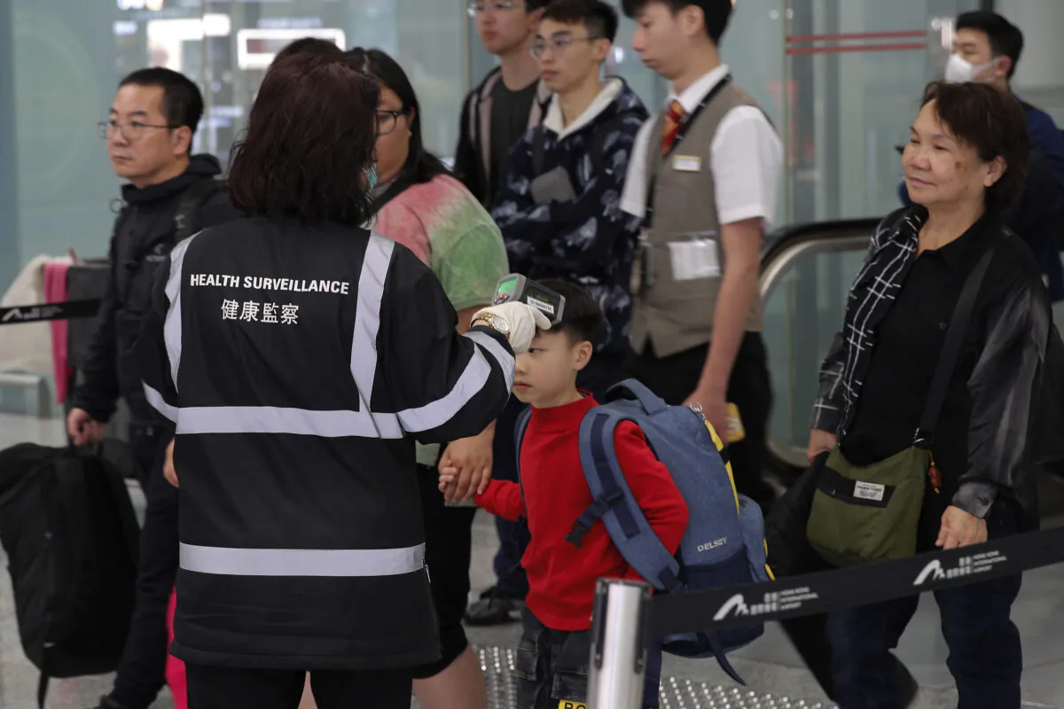 A health surveillance officer uses a device to check temperature of passengers near the immigration counters at the Hong Kong International airport, on Jan. 4, 2020. (AP Photo/Andy Wong)