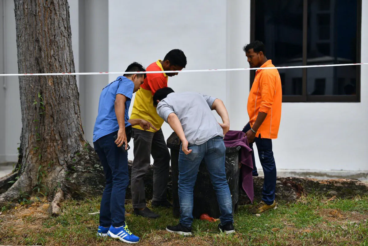 Police officers and cleaners inspect the contents of a bin at a rubbish chute, after a baby was found alive among rubbish in a bin at a public housing estate in Singapore, January 7, 2020. (Lim Yaohui/The Straits Times via Reuters)