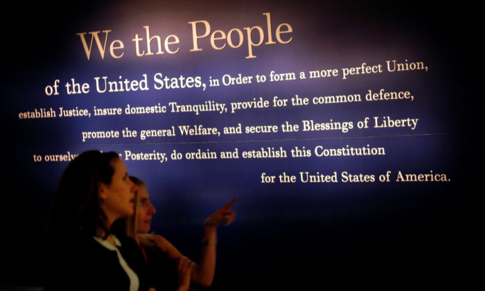Two women walk past a painting of the beginning of the U.S. Constitution during a preview of the National Constitution Center in Philadelphia, Penn., on July 1, 2003. (William Thomas Cain/Getty Images)
