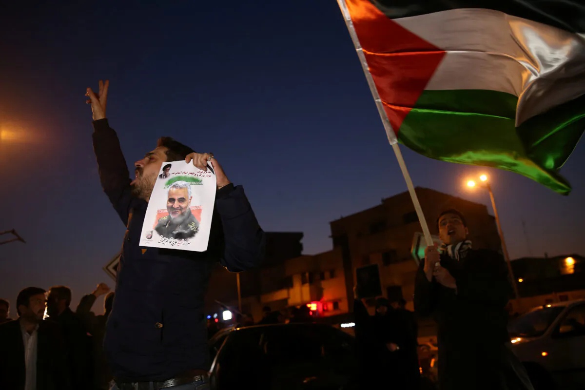 A man holds a picture of late Iranian General Qassem Soleimani, as people celebrate in the street after Iran launched missiles at U.S.-led forces in Iraq, in Tehran, Iran on Jan. 8, 2020. (Nazanin Tabatabaee/WANA (West Asia News Agency) via Reuters)
