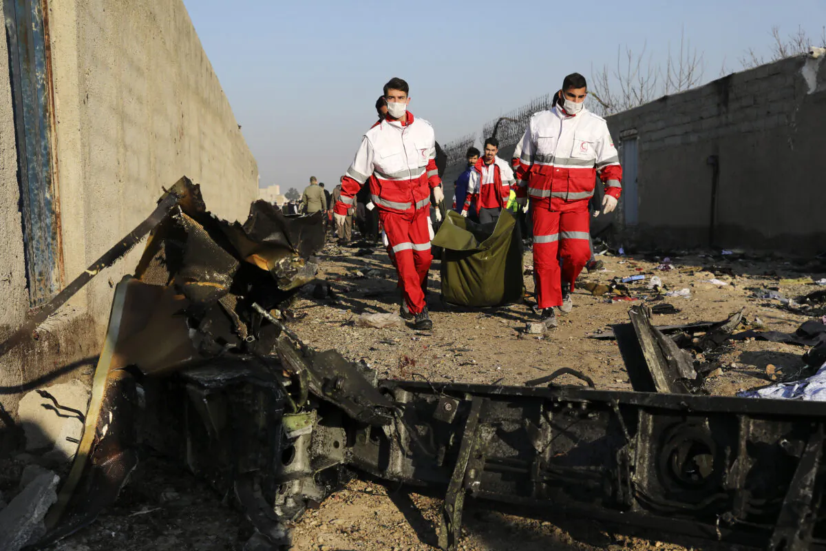 Rescue workers carry the body of a victim of an Ukrainian plane crash among debris of the plane in Shahedshahr, southwest of the capital Tehran, Iran on Jan. 8, 2020. (Ebrahim Noroozi/AP Photo)