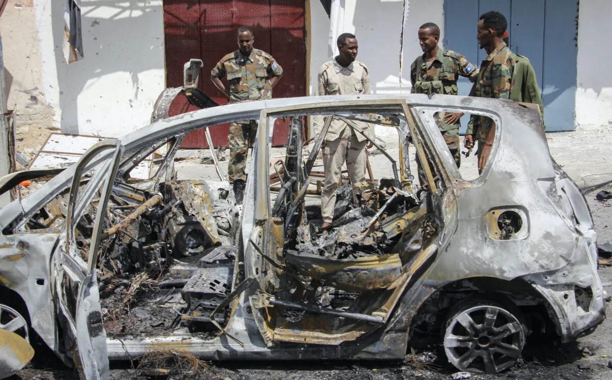 Security forces and others stand by the wreckage of vehicles after a vehicle bomb attack on a security checkpoint located near the presidential palace, in Mogadishu, Somalia on Wednesday, Jan. 8, 2020. (Farah Abdi Warsameh/AP)