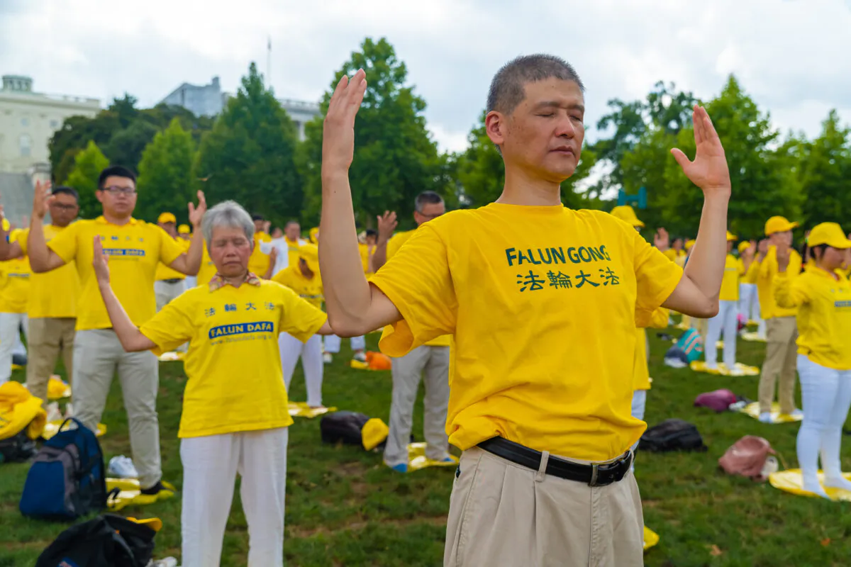 Falun Gong practitioners perform the exercises at a rally commemorating the 20th anniversary of the persecution of Falun Gong in China, on the West Lawn of Capitol Hill on July 18, 2019. (Mark Zou/The Epoch Times)