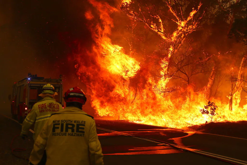 Fire and Rescue personal run to move their truck as a bushfire burns next to a major road and homes on the outskirts of the town of Bilpin in Sydney, Australia, on Dec. 19, 2019. (David Gray/Getty Images)