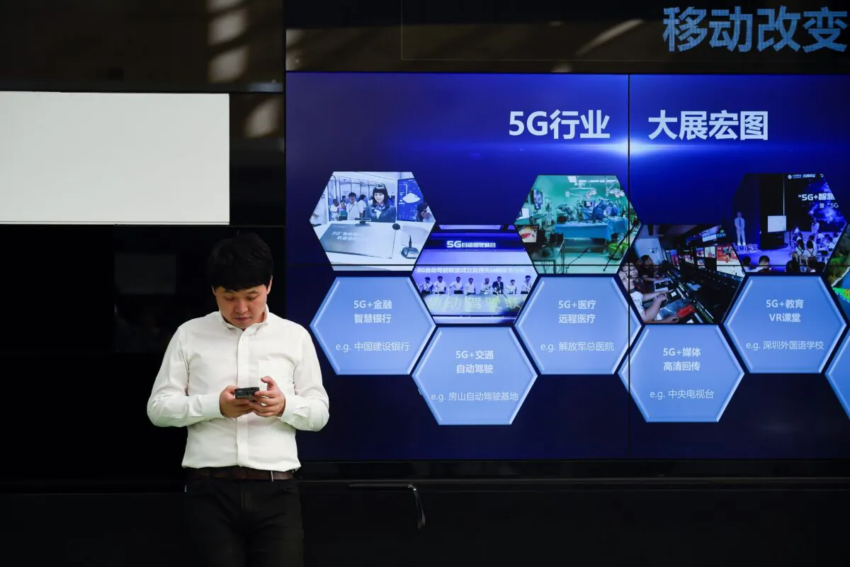 A man uses his mobile phone in front of a screen showing China's 5G industry outside a telecom office in Beijing on Sept. 25, 2019. (WANG ZHAO/AFP via Getty Images)