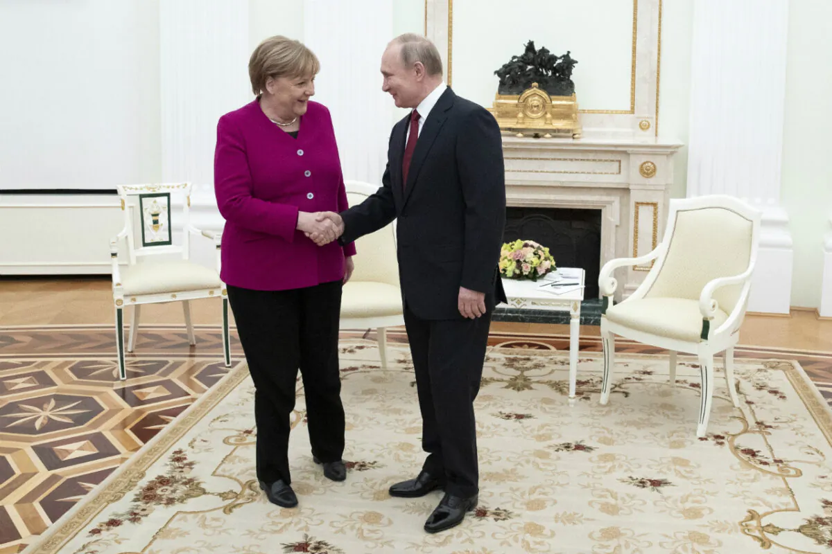 Russian President Vladimir Putin and German Chancellor Angela Merkel greet each other prior to the talks in the Kremlin in Moscow, Russia, on Jan. 11, 2020. (Pavel Golovkin/Pool/AP Photo)