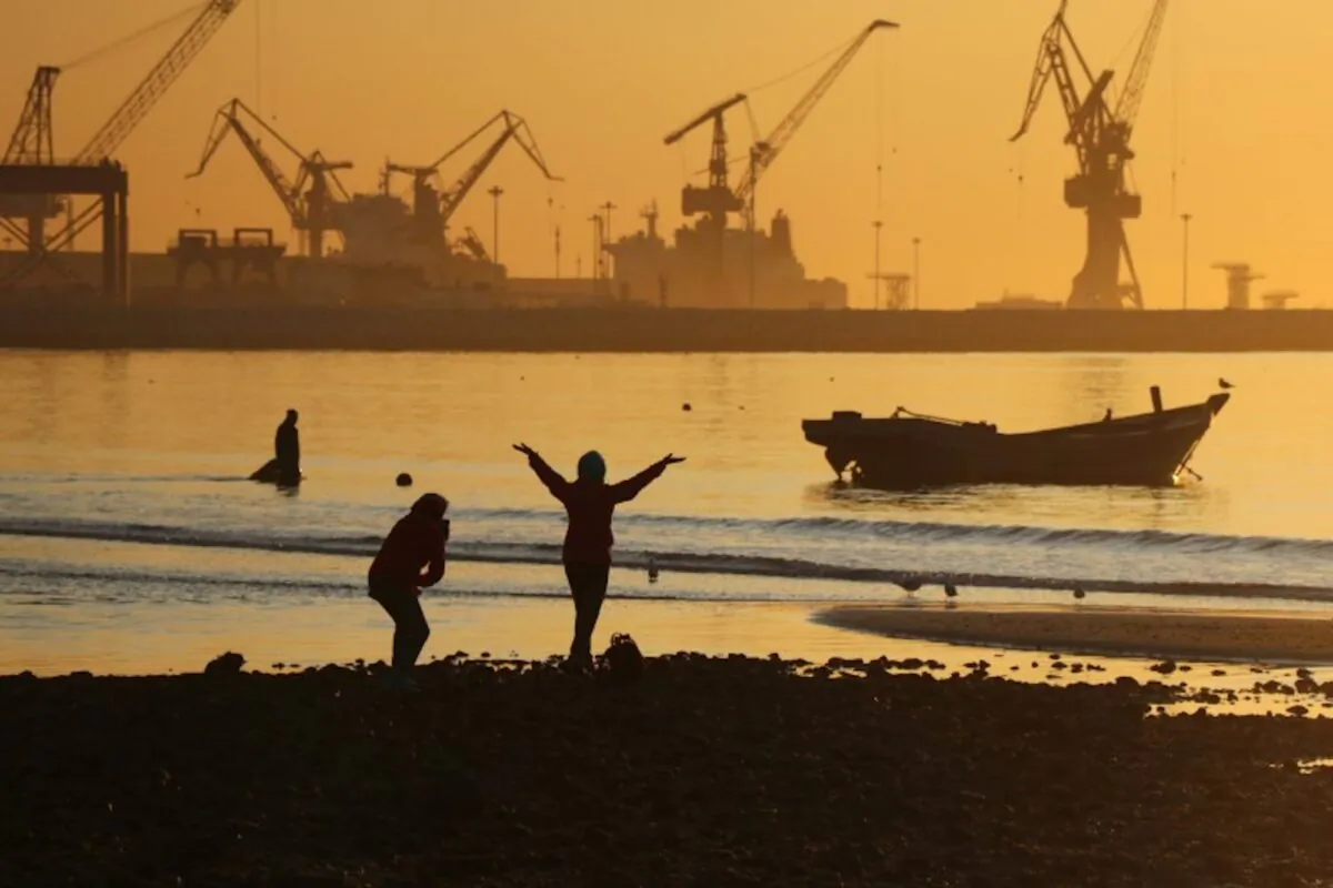 People enjoy the beach near a port during sunrise in Qinhuangdao, Hebei Province, China on Oct. 15, 2019. (Reuters)