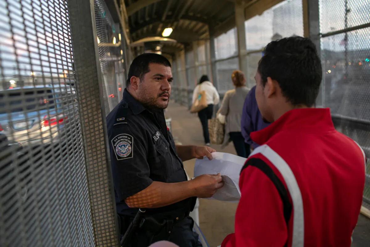 A U.S. Customs and Border Protection officer checks immigration documents as a Honduran asylum seeker arrives at the international bridge from Mexico to the United States next to the border town of Matamoros, Mexico, on Dec. 9, 2019.  (John Moore/Getty Images)