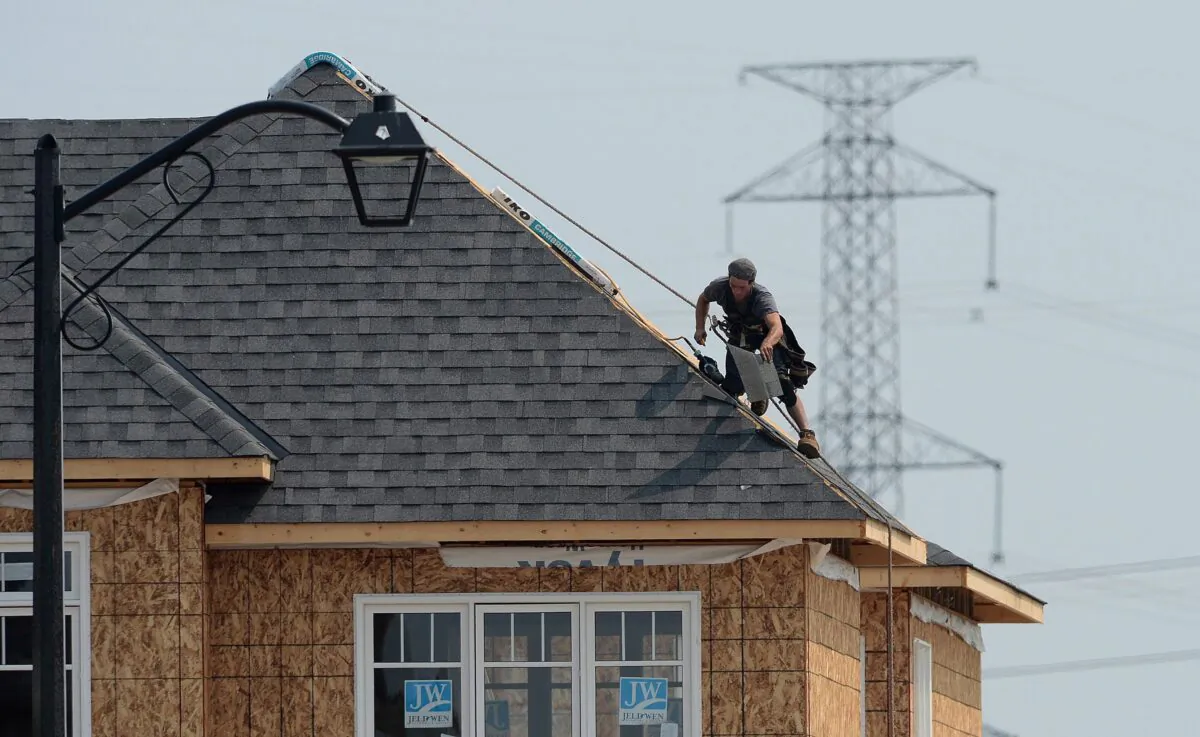 A construction worker shingles the roof of a new home in a housing development in Ottawa in a file photo. (The Canadian Press/Sean Kilpatrick)