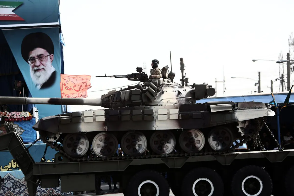 An Iranian soldier sitting atop a T-72 tank as it rolls past a portrait of Iran's supreme leader, Ali Khamenei during the Army Day parade in Tehran on April 18, 2015. Behrouz Mehri/AFP via Getty Images