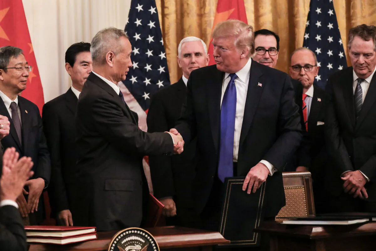 Chinese Vice Premier Liu He (L) and U.S. President Donald Trump during the signing of phase one of a trade deal, surrounded by officials, in the East Room of the White House in Washington on Jan. 15, 2020. (Charlotte Cuthbertson/The Epoch Times)
