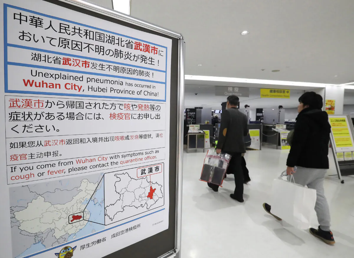 Passengers walk past a sign at Narita Airport in Chiba prefecture on January 16, 2020. Japan has confirmed a case of a mystery virus that first emerged in China and is from the same family as the deadly SARS pathogen, authorities said on January 16. (STR/JIJI PRESS/AFP via Getty Images)