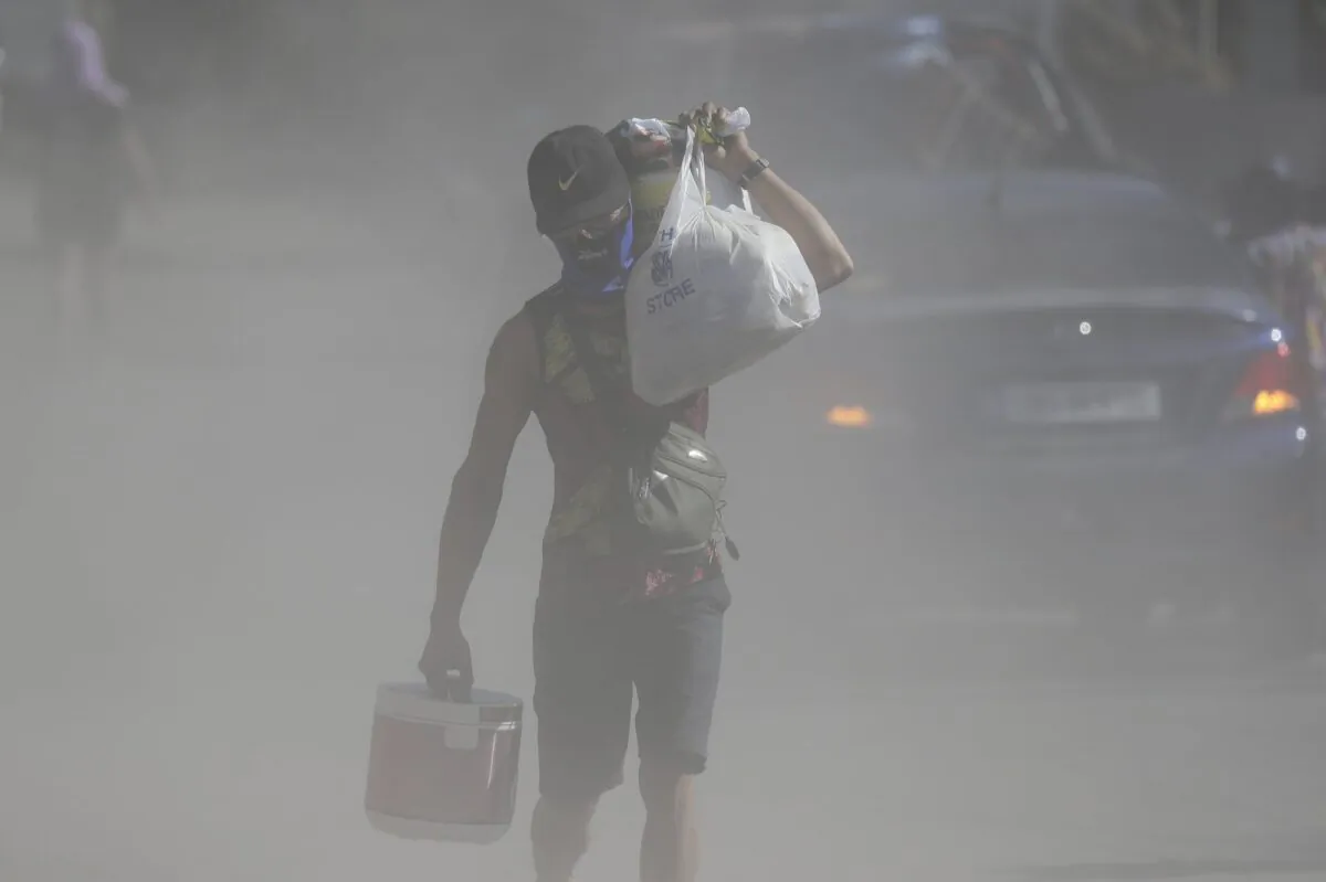 A man walks the his belongings through clouds of ash kicked up on a road as authorities enforced total evacuation of residents living near Taal volcano in Agoncillo town, Batangas province, southern Philippines on Jan. 16, 2020. (Aaron Favila/AP Photo)