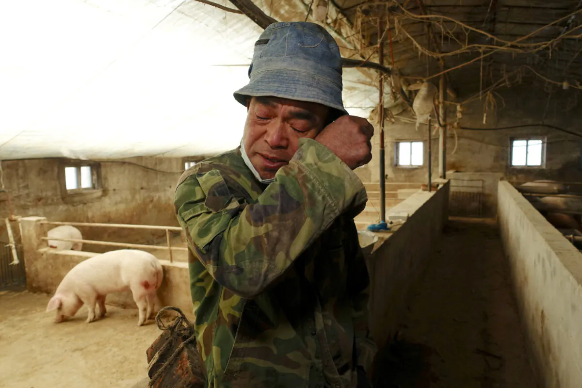 FILE PHOTO: Pig farmer Han Yi wipes his tears as he speaks to Reuters on his farm at a village in Changtu county, Liaoning province, China January 17, 2019. Picture taken January 17, 2019. REUTERS/Ryan Woo - RC1B97D839E0/File Photo