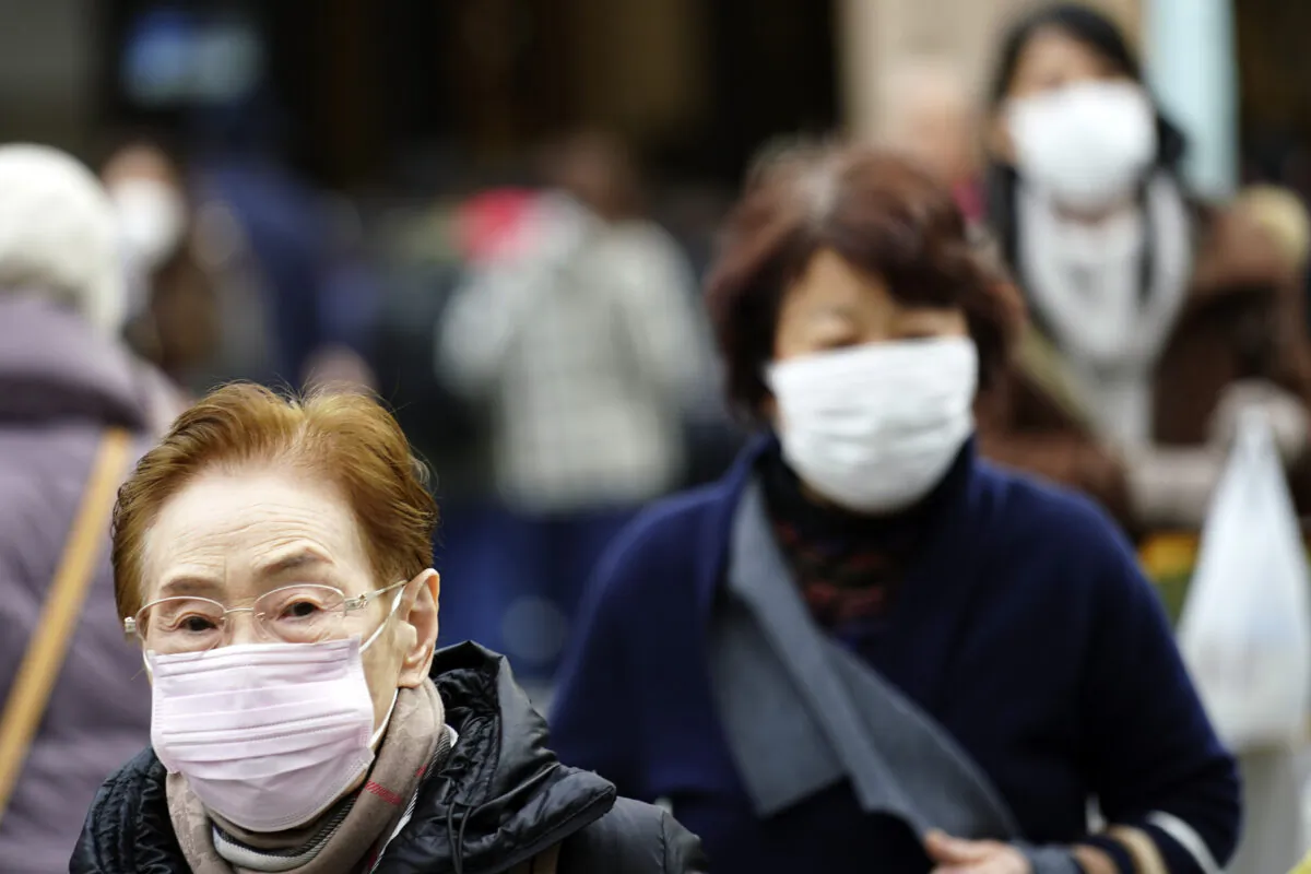 Pedestrians wear protective masks as they walk through a shopping district in Tokyo on Jan. 16, 2020. Japan's government said a man treated for pneumonia after returning from China has tested positive for the new coronavirus identified as a possible cause of an outbreak in the Chinese city of Wuhan. (Eugene Hoshiko/AP)