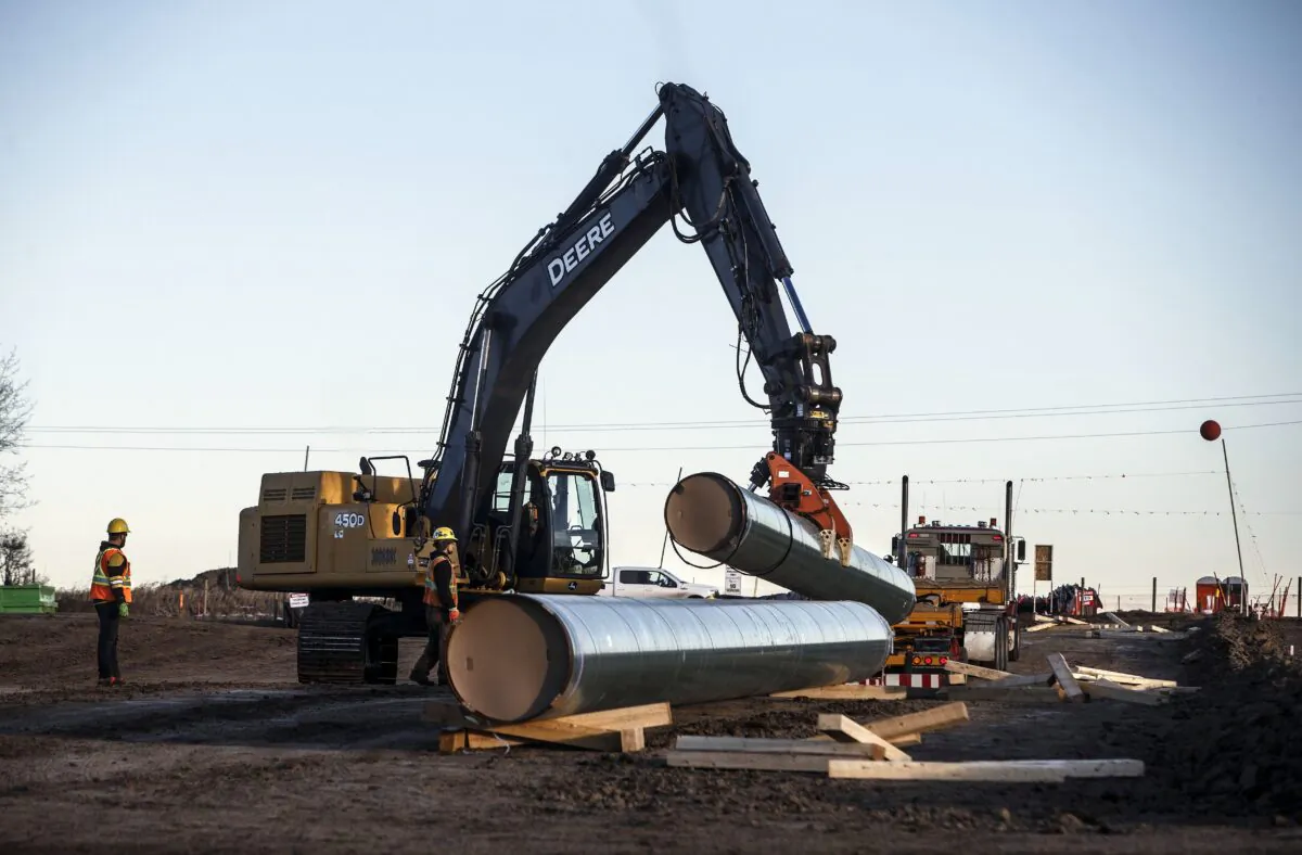 Workers unload pipe to start right-of-way construction for the Trans Mountain Expansion Project, in Acheson, Alta., on Dec. 3, 2019. (The Canadian Press/Jason Franson)