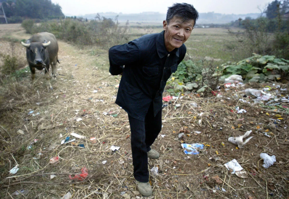 A farmer pulls his water buffalo along garbage-strewn trails in a village outside of Yueyang, Henan Province, China on Oct. 30, 2004. More than half of China's peasants are so poor that they are unable to look after themselves. (Frederic J. Brown/AFP via Getty Images)