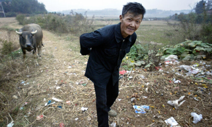 A farmer pulls his water buffalo along garbage-strewn trails in a village outside of Yueyang, Henan Province, China on Oct. 30, 2004. More than half of China's peasants are so poor that they are unable to look after themselves. (Frederic J. Brown/AFP via Getty Images)