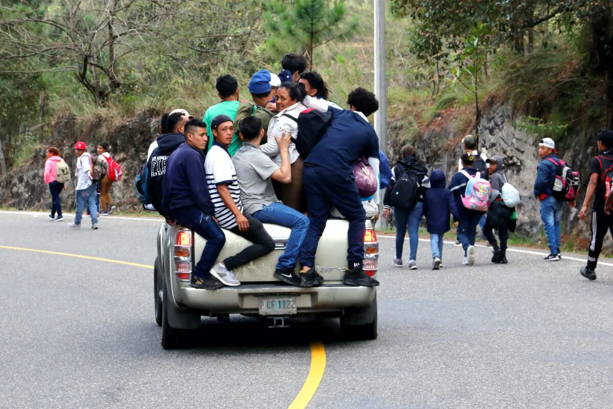 People, part of a caravan of migrants heading toward the United States, travel on the back of a truck as others walk along a road in Agua Caliente, Honduras, on Jan. 16, 2020. (Stringer/Reuters)