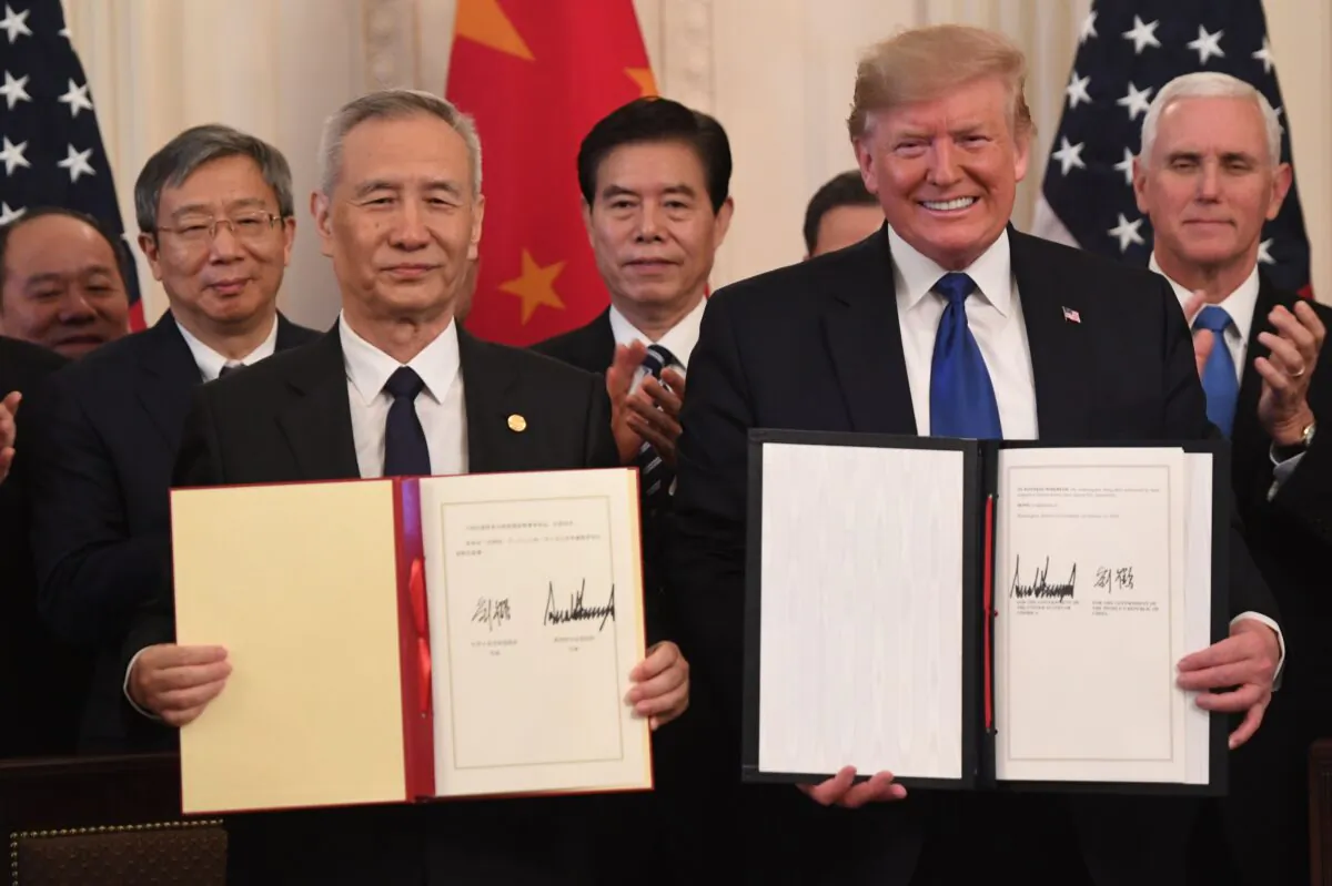 Chinese Vice Premier Liu He and U.S. President Donald Trump display the signed trade agreement between the United States and China in the East Room of the White House in Washington, on Jan. 15, 2020. (Saul Loeb/AFP/Getty Images)