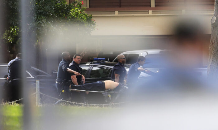 Honolulu police carry an injured fellow officer after a shooting and domestic incident at a residence on Hibiscus Road near Diamond Head in Honolulu, Hawaii, on Jan. 19, 2020. (Jamm Aquino/Honolulu Star-Advertiser).