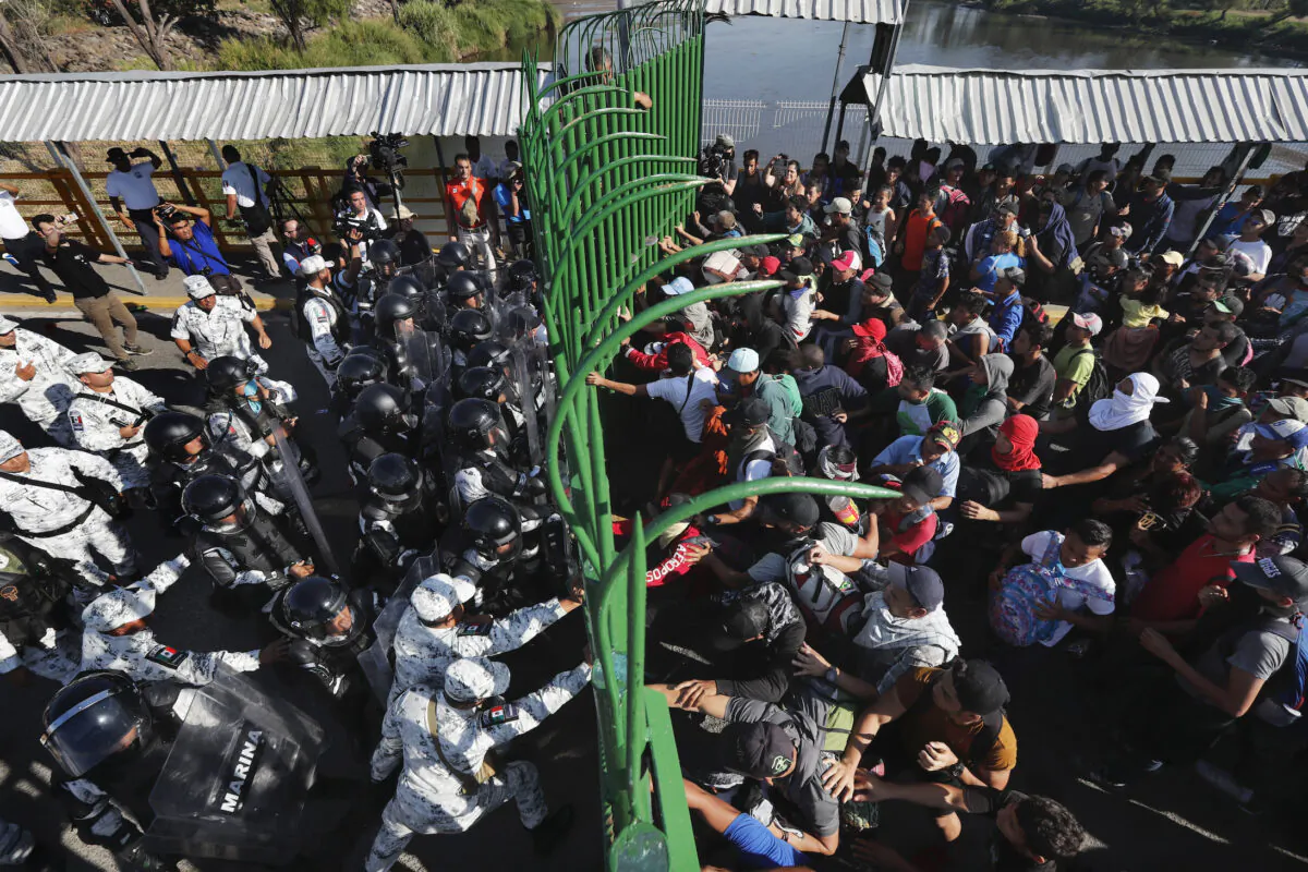 Migrants charge on the Mexican National Guardsmen at the border crossing between Guatemala and Mexico in Tecun Uman, Guatemala, on Jan. 18, 2020. (Marco Ugarte/AP Photo)