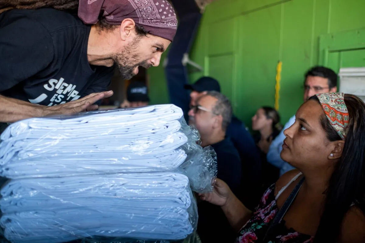 A man distributes supplies after breaking into a warehouse with supplies believed to have been from when Hurricane Maria struck the island in 2017 in Ponce, Puerto Rico, on Jan. 18, 2020. (Ricardo Arduengo/AFP via Getty Images)