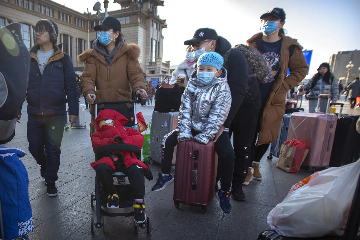 Travelers wear face masks as they walk outside of the Beijing Railway Station in Beijing on Jan. 20, 2020. China reported on Monday a sharp rise in the number of people infected with a new coronavirus, including the first cases in the capital. The outbreak coincides with the country's busiest travel period, as millions board trains and planes for the Lunar New Year holidays. (Mark Schiefelbein/AP)