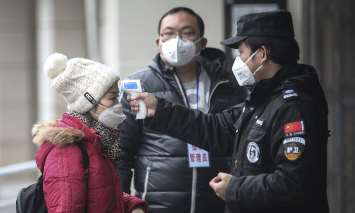 Security personnel check the temperature of passengers in the Wharf at the Yangtze River in Wuhan city, Hubei province, China, on January 22, 2020.  (Photo by Getty Images)