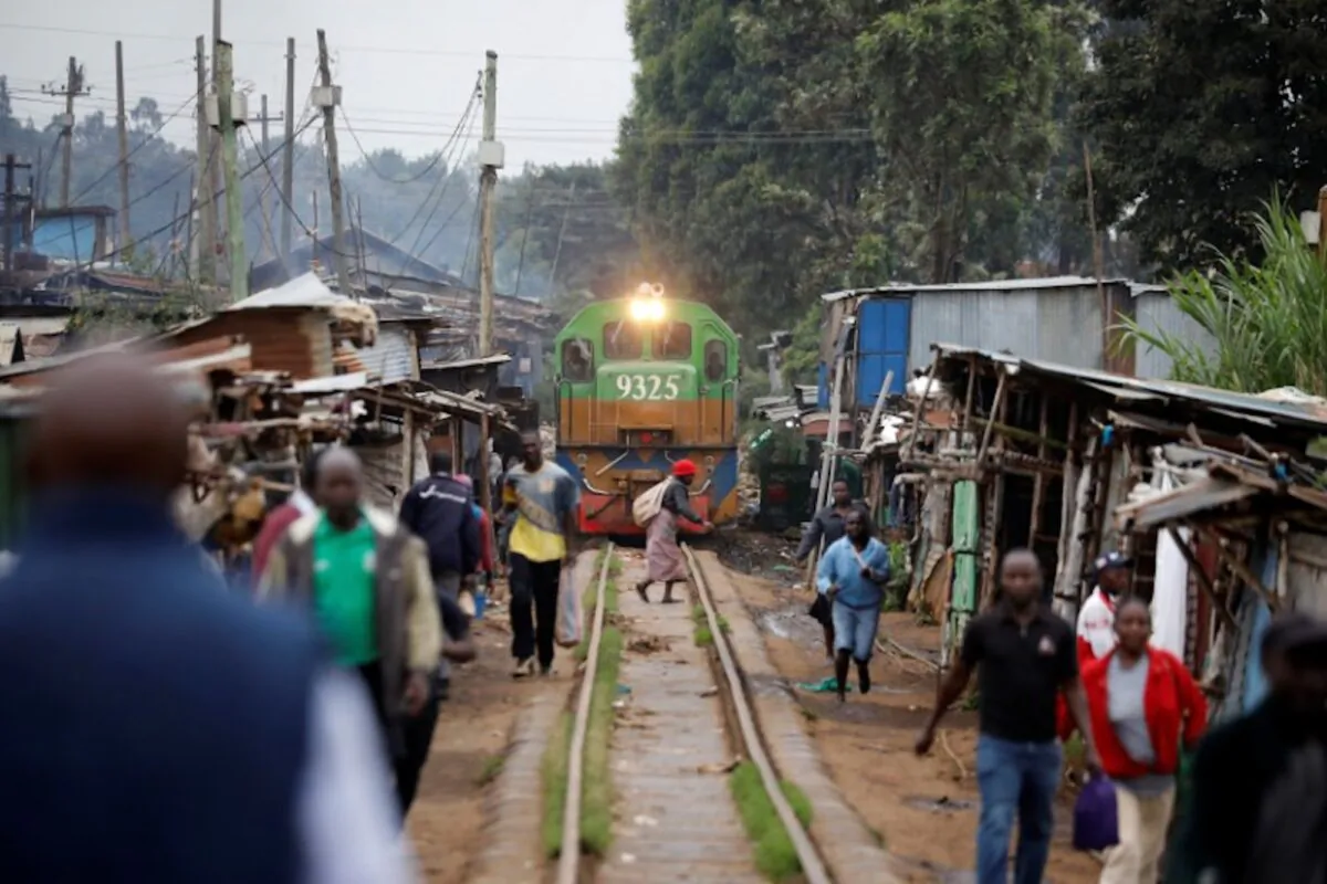A woman crosses a railway track just as a train approaches a makeshift train station in the Kibera slum of Nairobi, Kenya, on Nov. 29, 2019. (Baz Ratner/Reuters)