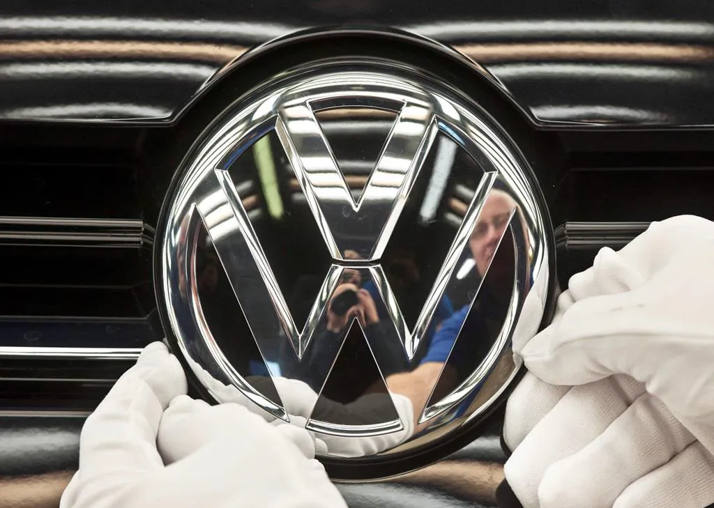 A worker fixes a sign on a Volkswagen Golf car during a press tour in Zwickau, Germany in a file photo. (Jens Meyer/The Canadian Press/AP)